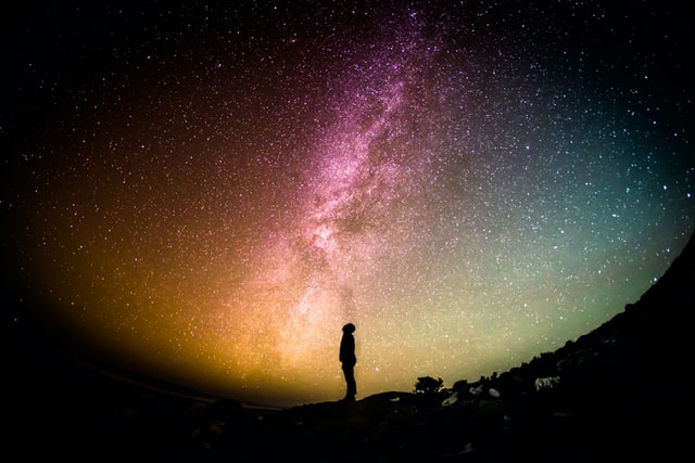 Man in sillhoute staring at the milky way with beautiful colors